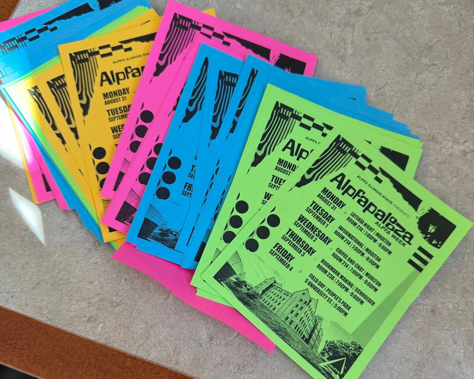 A fanned stack of Alpfapalooza flyers printed in black on neon pink, blue, yellow and green paper, listing the week's events from Monday August 31 to Friday September 4