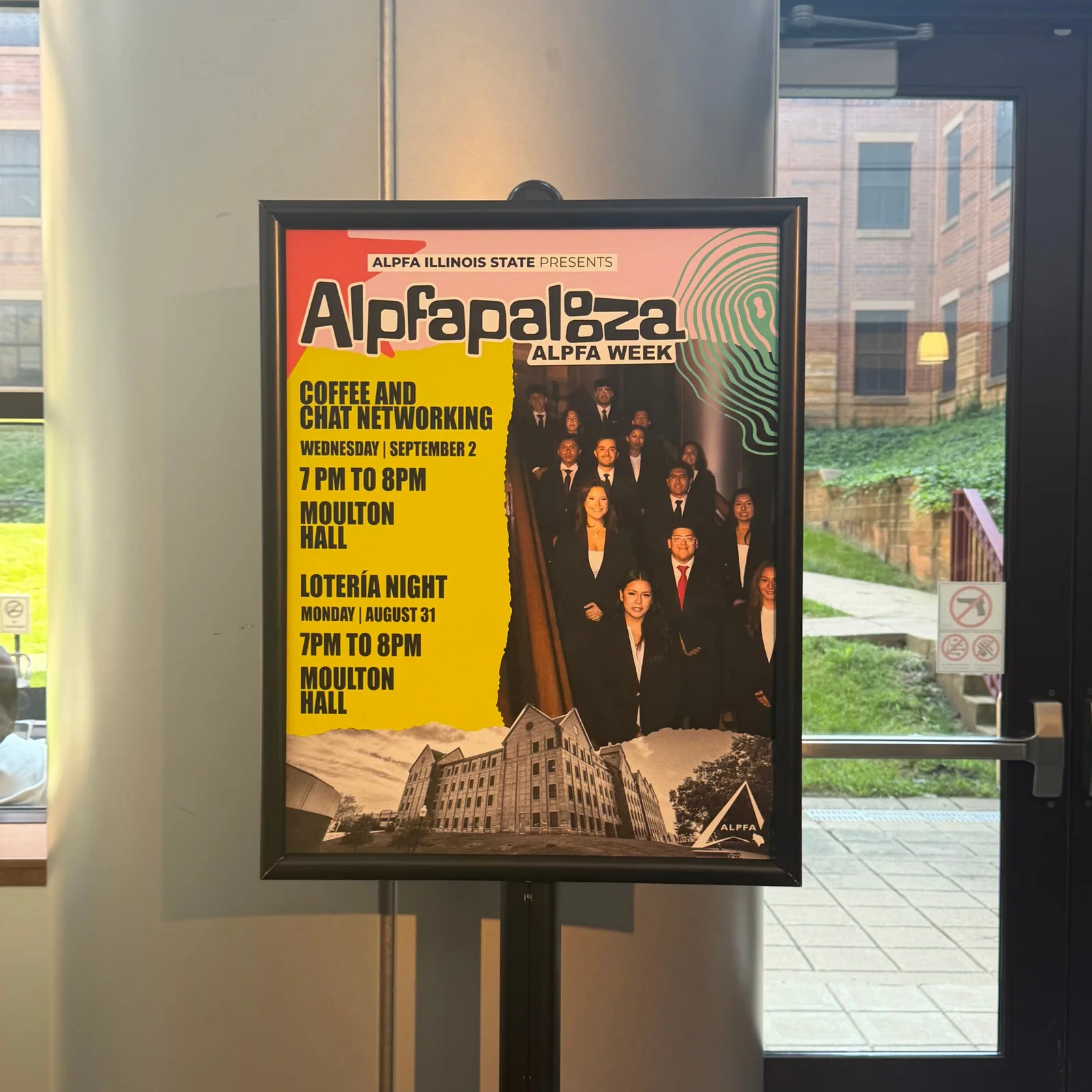 Full-color Alpfapalooza poster on a display stand, promoting Coffee and Chat Networking and Loter&iacute;a Night in Moulton Hall, with a photo of chapter members in suits