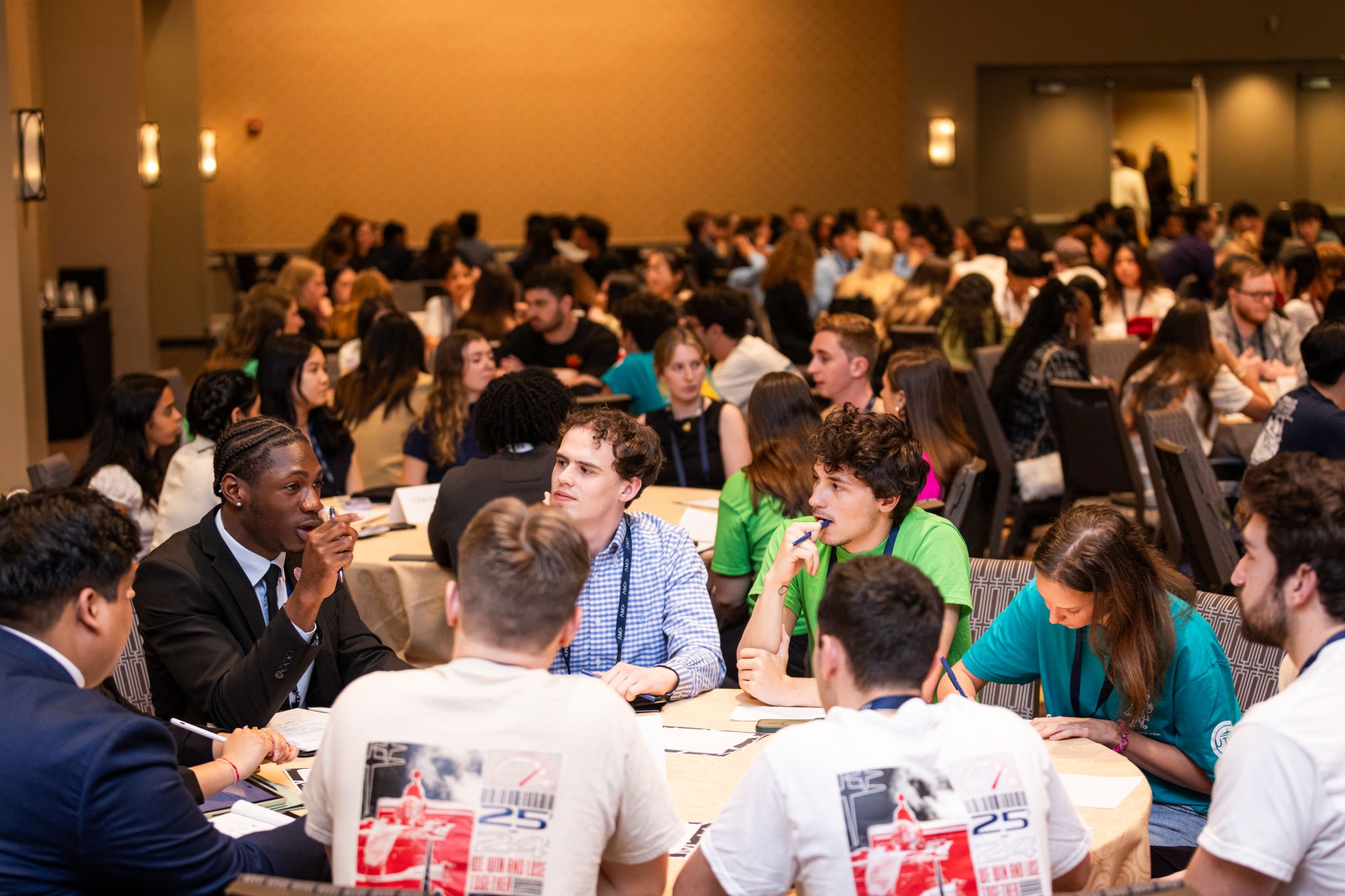 confrence photo with the back of the ama t-shirts shown in a table discussion