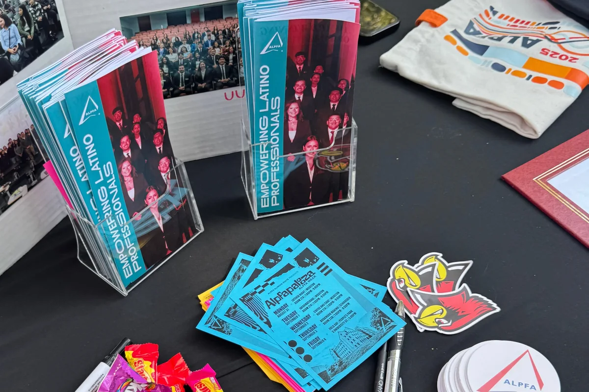 An ALPFA recruitment table with stacks of Empowering Latino Professionals brochures, blue Alpfapalooza flyers and ALPFA stickers